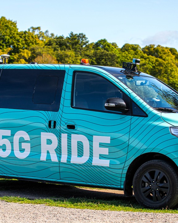 Photo from the side of the blue 5G Ride minibus with cameras on the roof