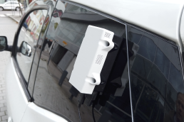 A white sensor box on the outside of a car window
