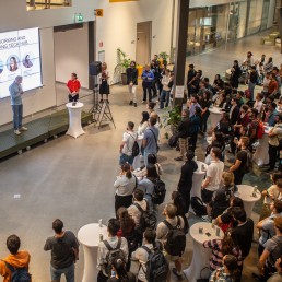A group of university students listening to a man presenting in front of a large screen