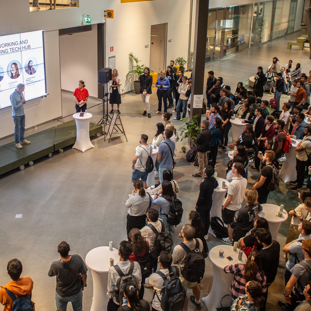 A group of university students listening to a man presenting in front of a large screen
