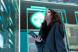 Female hacker breaching network security with advanced techniques, cyber defense in action. IT expert examines important hybrid war intelligence on a big screen, gaining access.