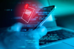 A hand holding a smartphone. A blue filter with code covers the image. An illustrated warningmessage pops up on the phone